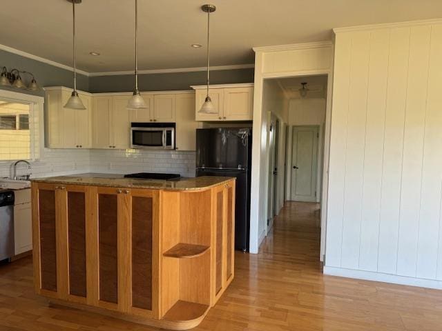 kitchen featuring pendant lighting, appliances with stainless steel finishes, a center island, light hardwood / wood-style flooring, and crown molding