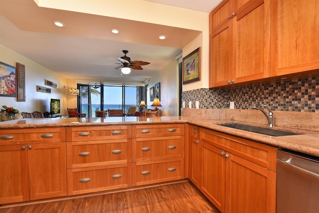 kitchen featuring dishwasher, backsplash, sink, light hardwood / wood-style floors, and kitchen peninsula