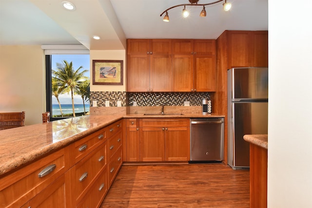 kitchen featuring appliances with stainless steel finishes, dark hardwood / wood-style flooring, tasteful backsplash, light stone counters, and sink