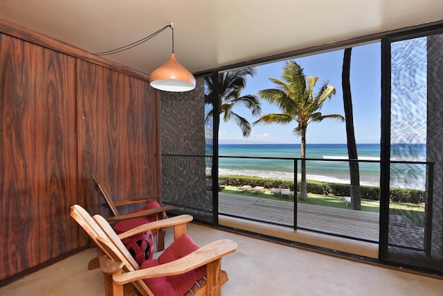 sitting room featuring a view of the beach, a water view, and wooden walls