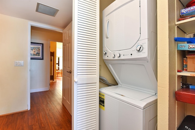 clothes washing area featuring dark hardwood / wood-style floors and stacked washer / drying machine