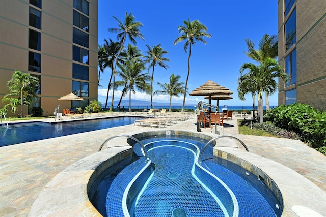 view of pool featuring a water view and a hot tub