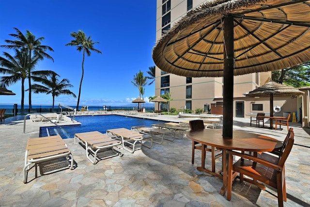 view of pool featuring a water view and a patio