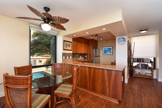 kitchen with dark wood-type flooring, sink, stainless steel fridge, tasteful backsplash, and kitchen peninsula