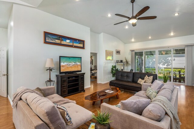 kitchen featuring pendant lighting, light hardwood / wood-style floors, lofted ceiling, a kitchen bar, and ceiling fan with notable chandelier