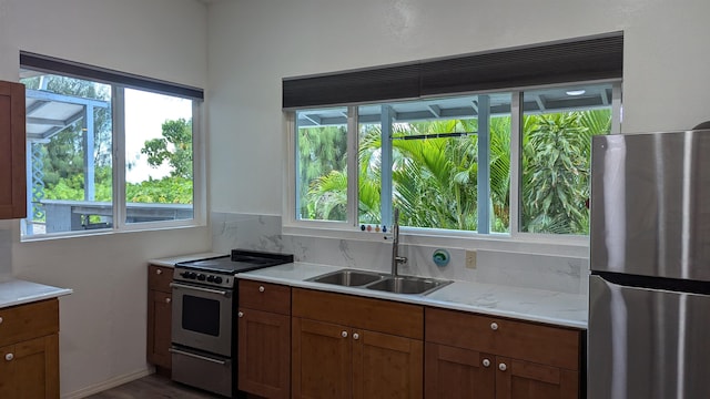 kitchen with appliances with stainless steel finishes, tasteful backsplash, a healthy amount of sunlight, and sink