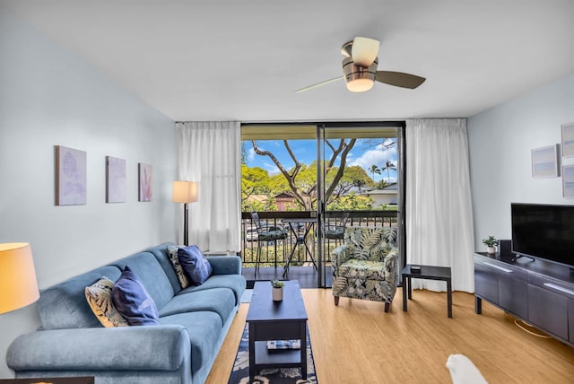 living room with expansive windows, wood finished floors, and a ceiling fan