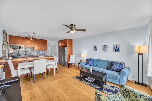 living room with a ceiling fan, light wood-style floors, a toaster, and baseboards
