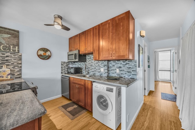 kitchen with washer / clothes dryer, light wood finished floors, a sink, decorative backsplash, and appliances with stainless steel finishes