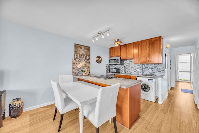 kitchen featuring stainless steel microwave, decorative backsplash, washer / dryer, and light wood-style floors