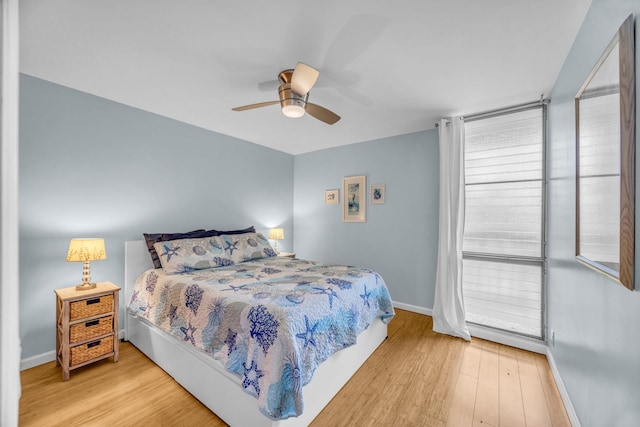 bedroom with ceiling fan, baseboards, and wood finished floors