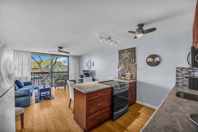 kitchen with a peninsula, a ceiling fan, stainless steel appliances, open floor plan, and floor to ceiling windows
