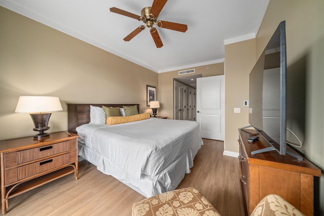 bedroom with light hardwood / wood-style floors, ceiling fan, and crown molding