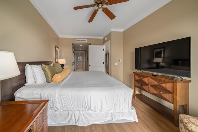 bedroom featuring light hardwood / wood-style flooring, ceiling fan, and crown molding