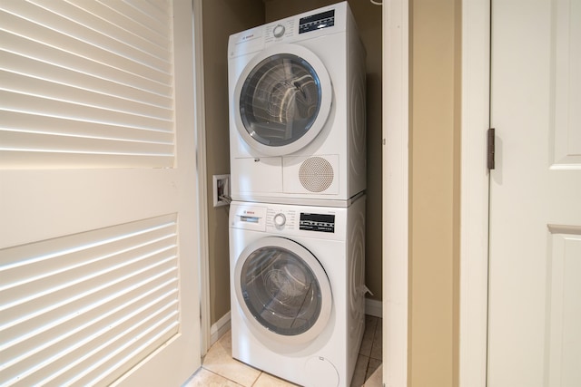 clothes washing area featuring light tile patterned floors and stacked washer / drying machine