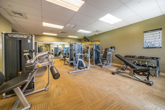 gym with a paneled ceiling and light carpet