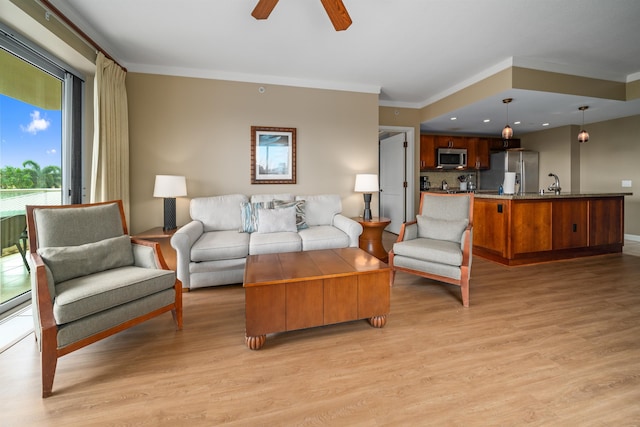 living room with light wood-type flooring, ceiling fan, ornamental molding, and sink