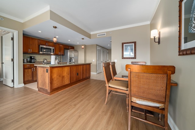 kitchen featuring decorative backsplash, appliances with stainless steel finishes, decorative light fixtures, light hardwood / wood-style flooring, and a center island