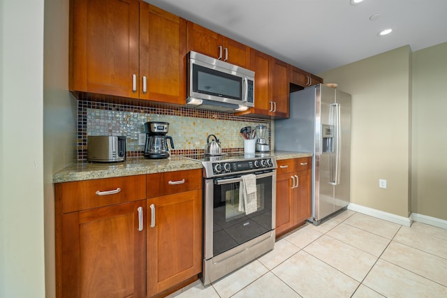 kitchen with light stone countertops, light tile patterned floors, stainless steel appliances, and tasteful backsplash