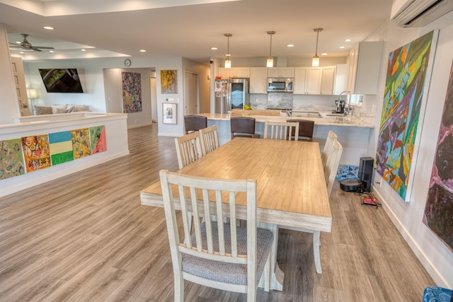 dining room with a ceiling fan, light wood-style flooring, a wall unit AC, and recessed lighting