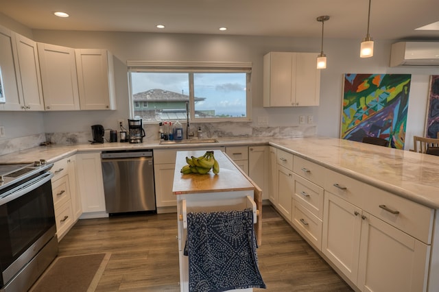 kitchen with appliances with stainless steel finishes, white cabinetry, light stone countertops, an AC wall unit, and dark hardwood / wood-style floors