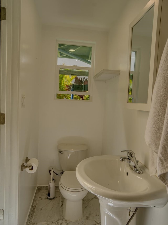 bathroom featuring marble finish floor, baseboards, toilet, and a sink