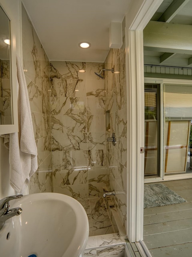 bathroom with tile walls, a marble finish shower, wood finished floors, recessed lighting, and a sink