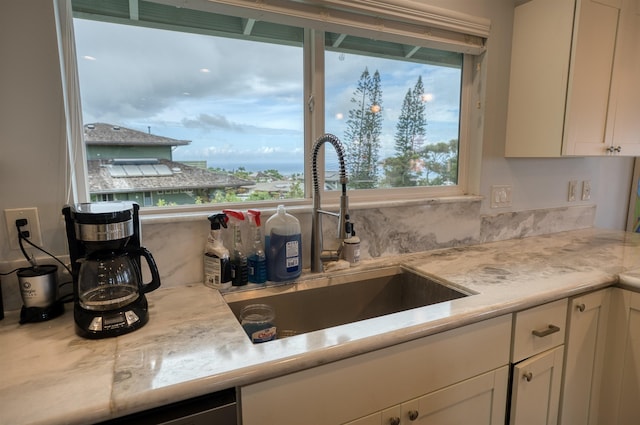kitchen with white cabinets, light countertops, a sink, and tasteful backsplash