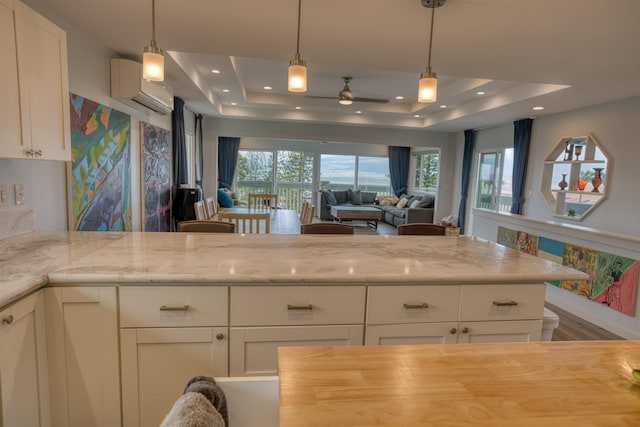 kitchen featuring ceiling fan, a wealth of natural light, an AC wall unit, and a raised ceiling