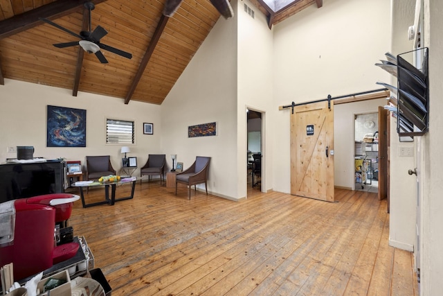 interior space featuring a barn door, visible vents, hardwood / wood-style flooring, ceiling fan, and beam ceiling