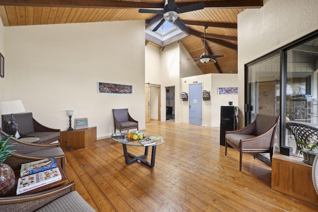 living area with wooden ceiling, hardwood / wood-style floors, a skylight, and beam ceiling