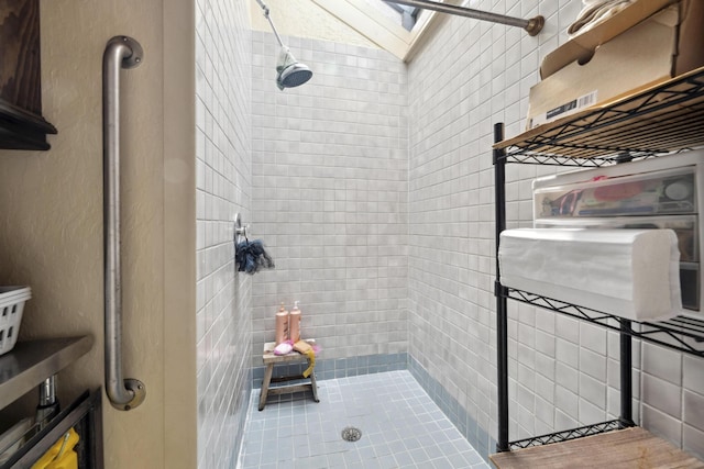 bathroom with a skylight and a tile shower