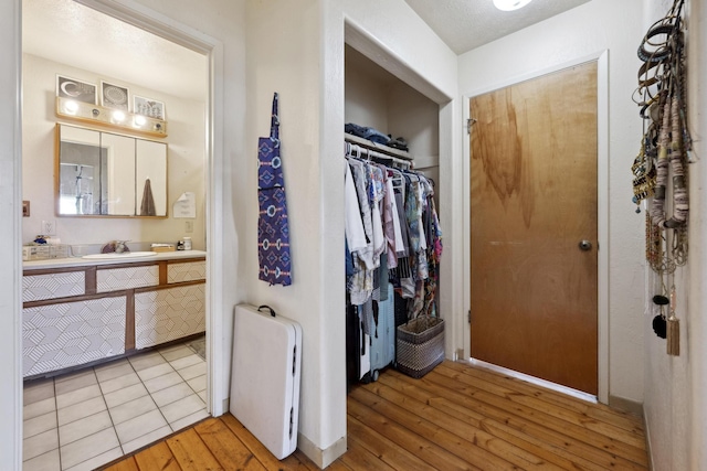 bathroom with a walk in closet, vanity, and hardwood / wood-style floors