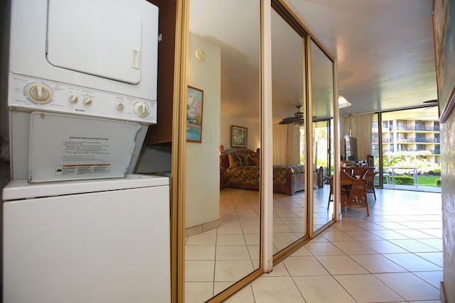 laundry room featuring light tile patterned floors and stacked washer / drying machine