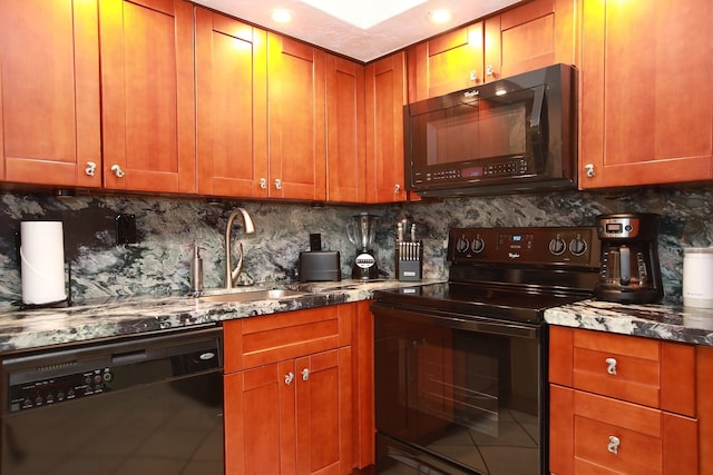 kitchen featuring a sink, decorative backsplash, brown cabinets, dark stone counters, and black appliances