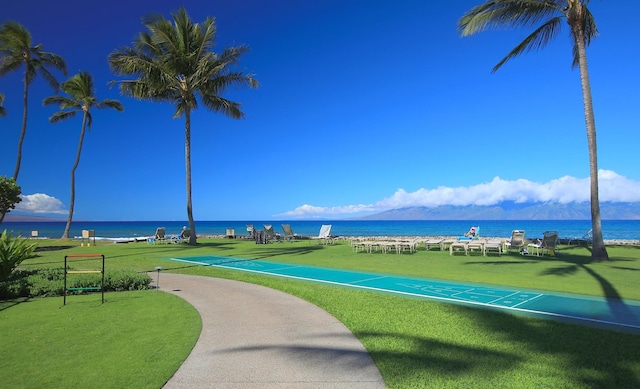 view of property's community with a lawn and a water view