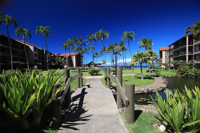 view of property's community with a water view and a lawn