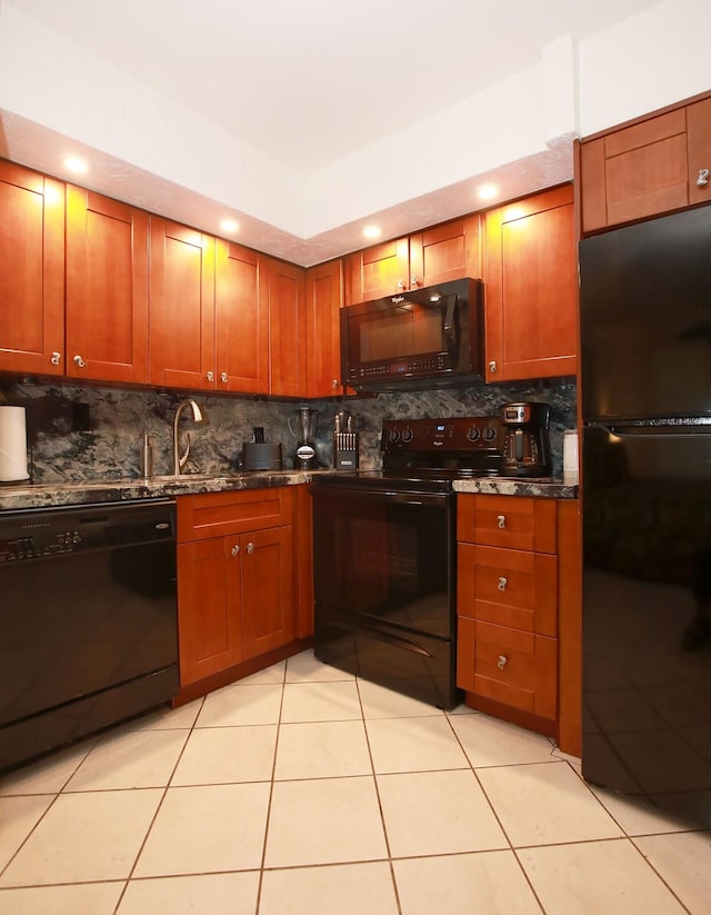 kitchen featuring dark stone counters, black appliances, sink, light tile patterned floors, and tasteful backsplash