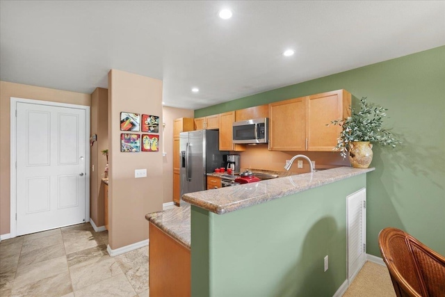 kitchen with stainless steel appliances, baseboards, a peninsula, and light brown cabinets