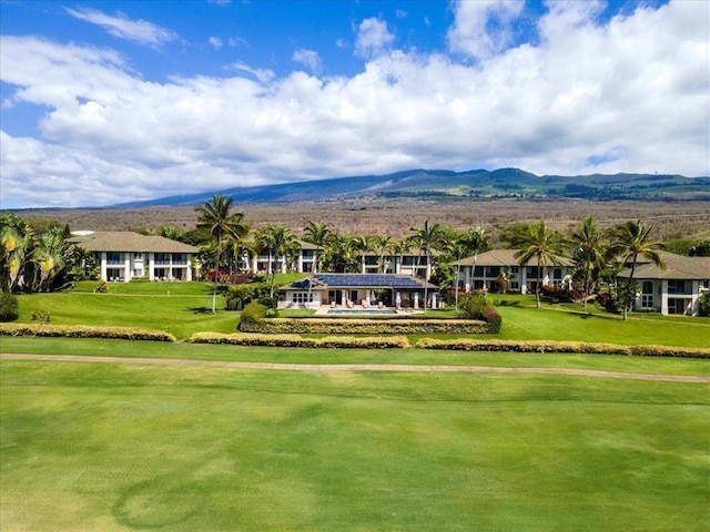 surrounding community with golf course view, a mountain view, and a yard