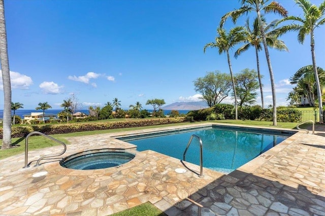 outdoor pool with an in ground hot tub, a mountain view, and a patio area