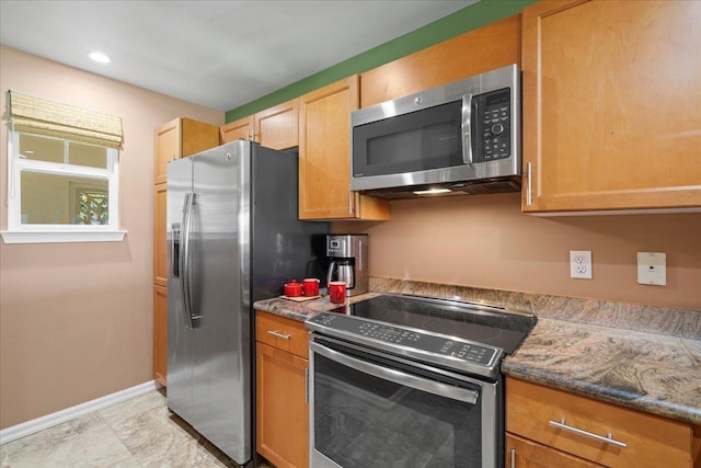 kitchen featuring baseboards, appliances with stainless steel finishes, and stone countertops