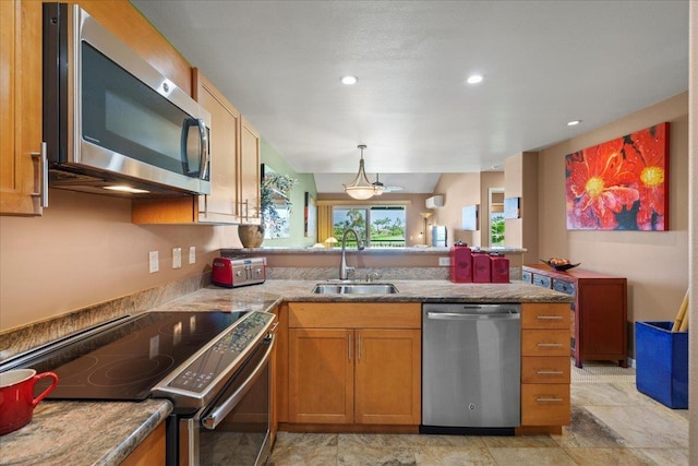 kitchen featuring a peninsula, recessed lighting, brown cabinets, a sink, and stainless steel appliances