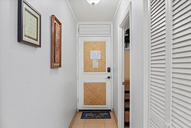 doorway to outside with ornamental molding and light tile patterned flooring