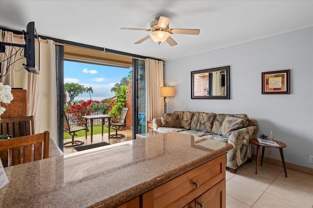 living area featuring baseboards, crown molding, ceiling fan, and light tile patterned floors
