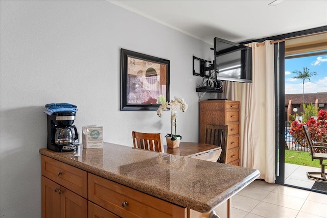 interior space with crown molding, a peninsula, light tile patterned floors, and dark stone counters