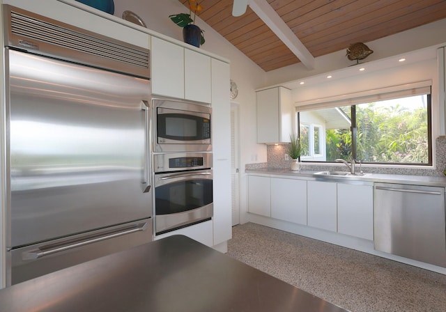 kitchen featuring white cabinets, built in appliances, vaulted ceiling with beams, a sink, and backsplash