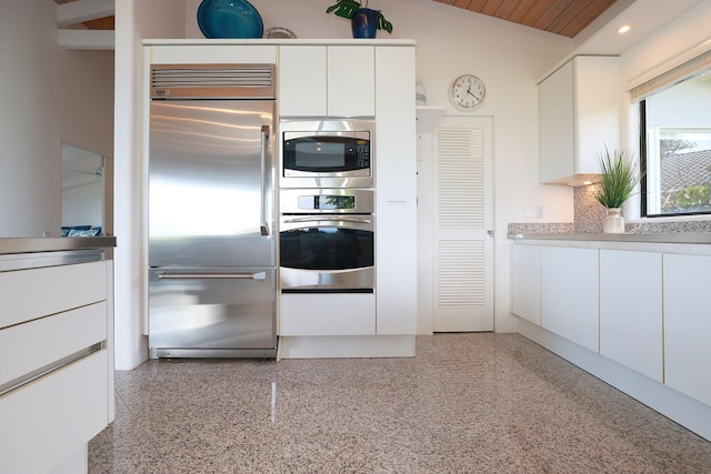 kitchen featuring built in appliances, light speckled floor, lofted ceiling, white cabinets, and light countertops