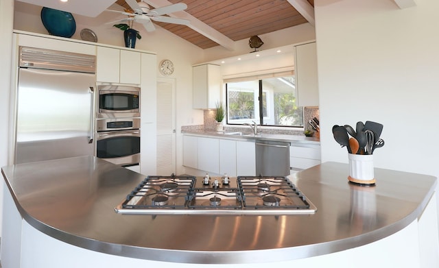 kitchen featuring tasteful backsplash, white cabinetry, vaulted ceiling with beams, and built in appliances