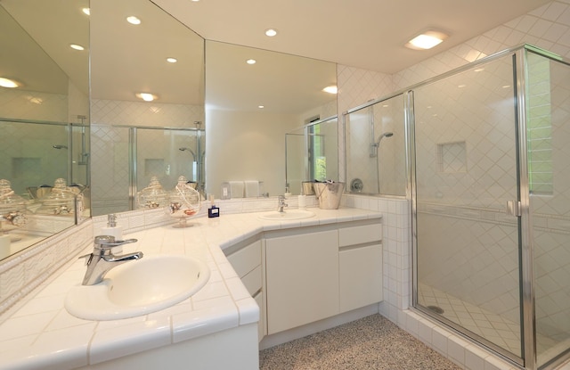 bathroom with double vanity, speckled floor, a sink, and a shower stall